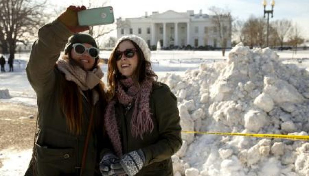 Unas turistas se toman una foto frente a la Casa Blanca, que está cubierta de nieve, en Washington